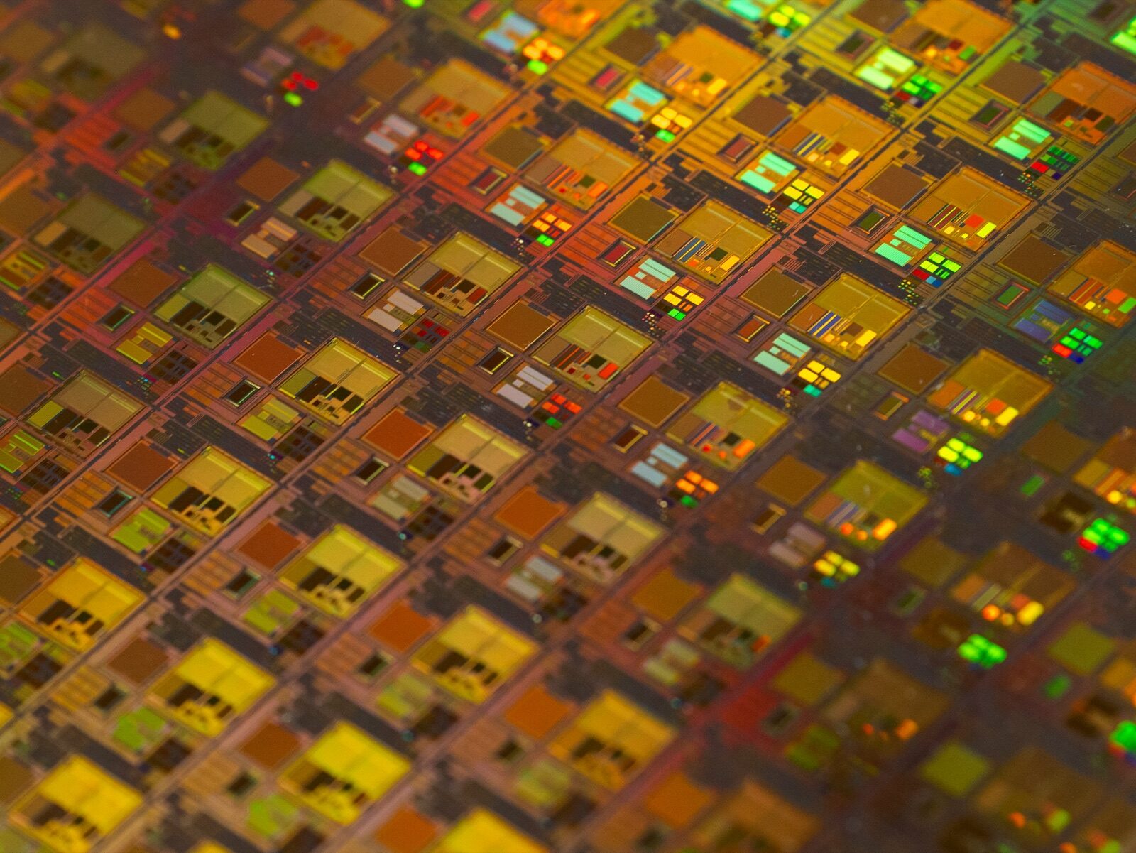 Iridescent semiconductor wafer surface showing die patterns for Incure M-Series™ UV focused beam electronics assembly